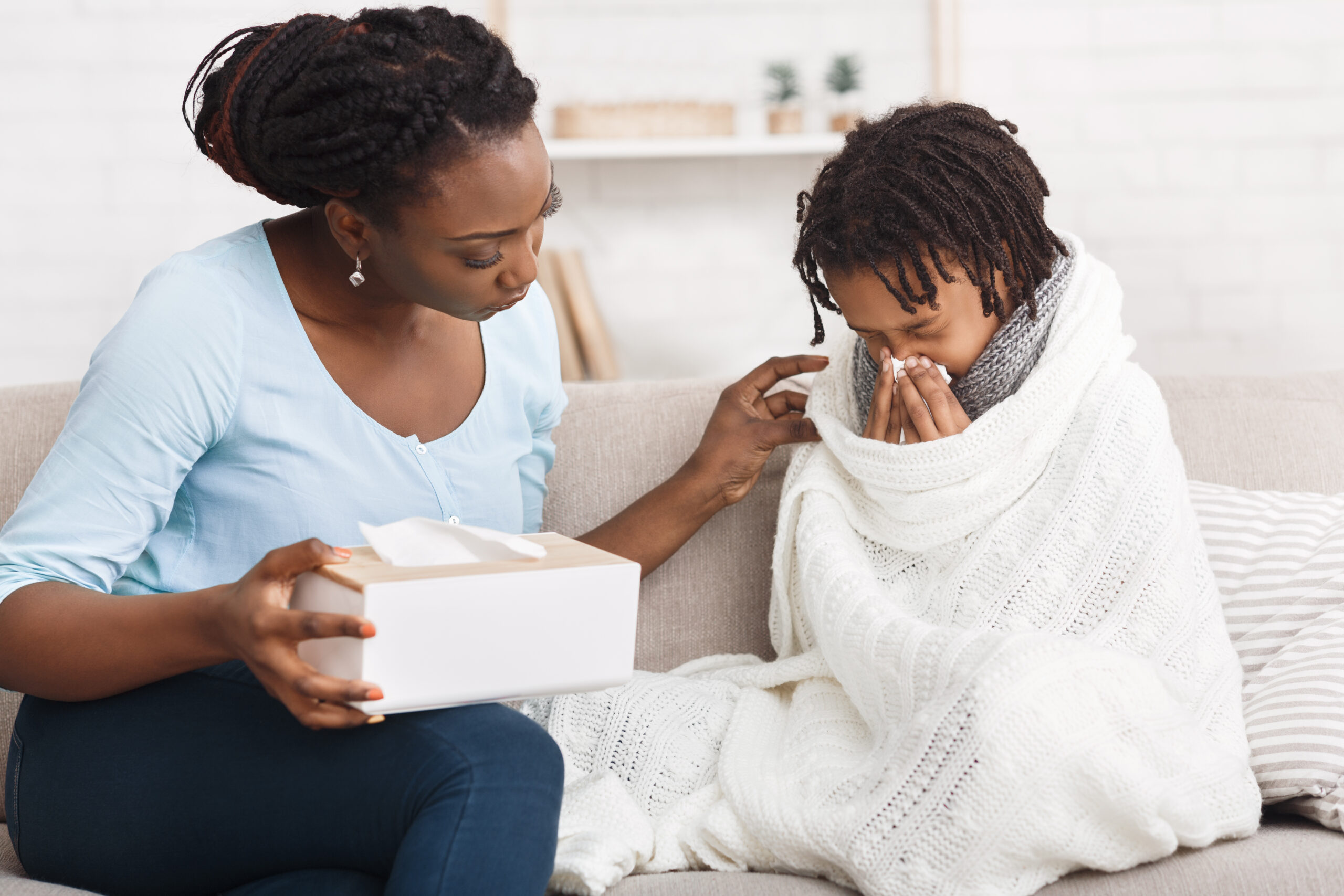 Black daughter sneezing, mother giving her napkins