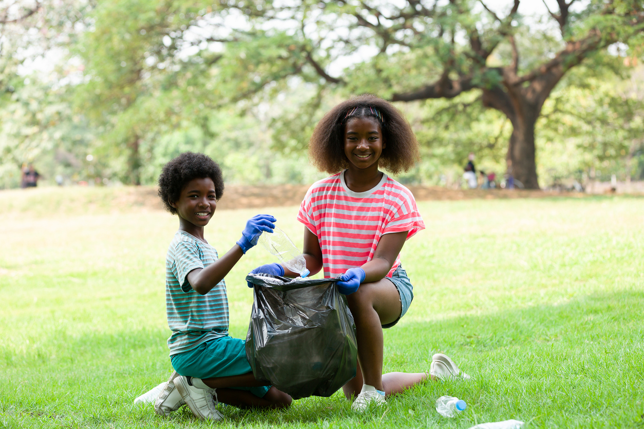 Group of children are collecting trash into a black bag, Kids volunteer charity environment.