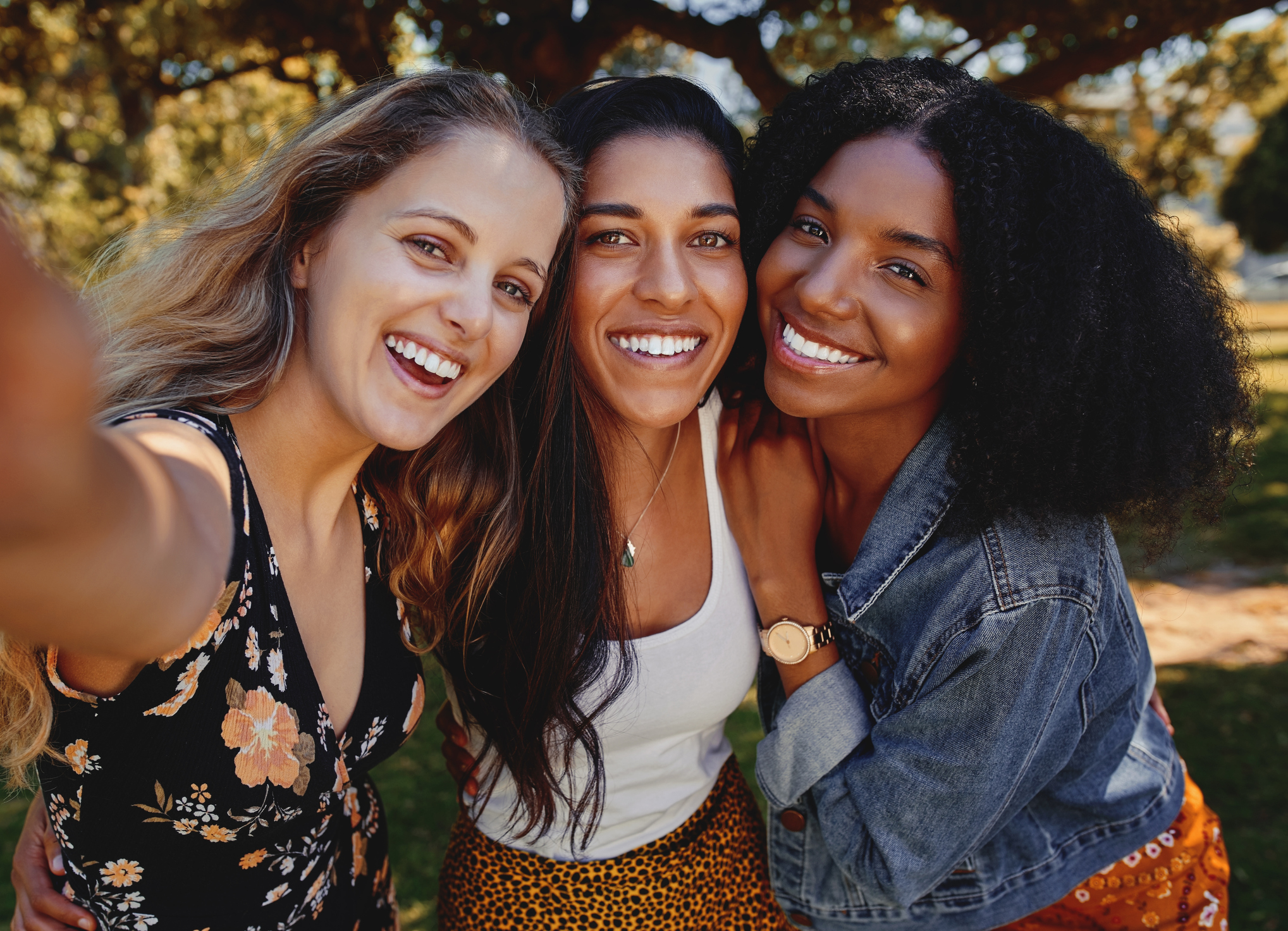 Close-up self portrait of smiling young multiethnic female friends taking selfie in the park - women taking a selfie in the park on a bright day