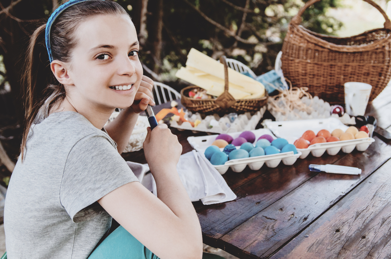 Child girl coloring Easter eggs