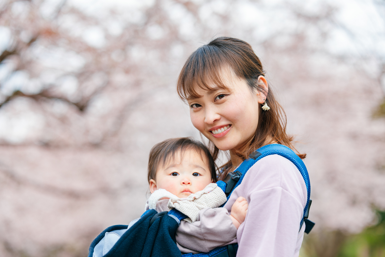 Mother embracing her small baby in front of cherry blossom tree