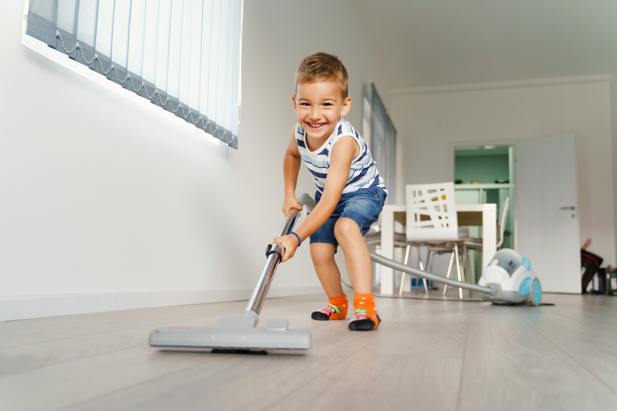 Little kid using vacuum cleaner at home - Small boy cleaning floor in apartment - Child doing housework having fun - front view full length in summer day - childhood development real people concept