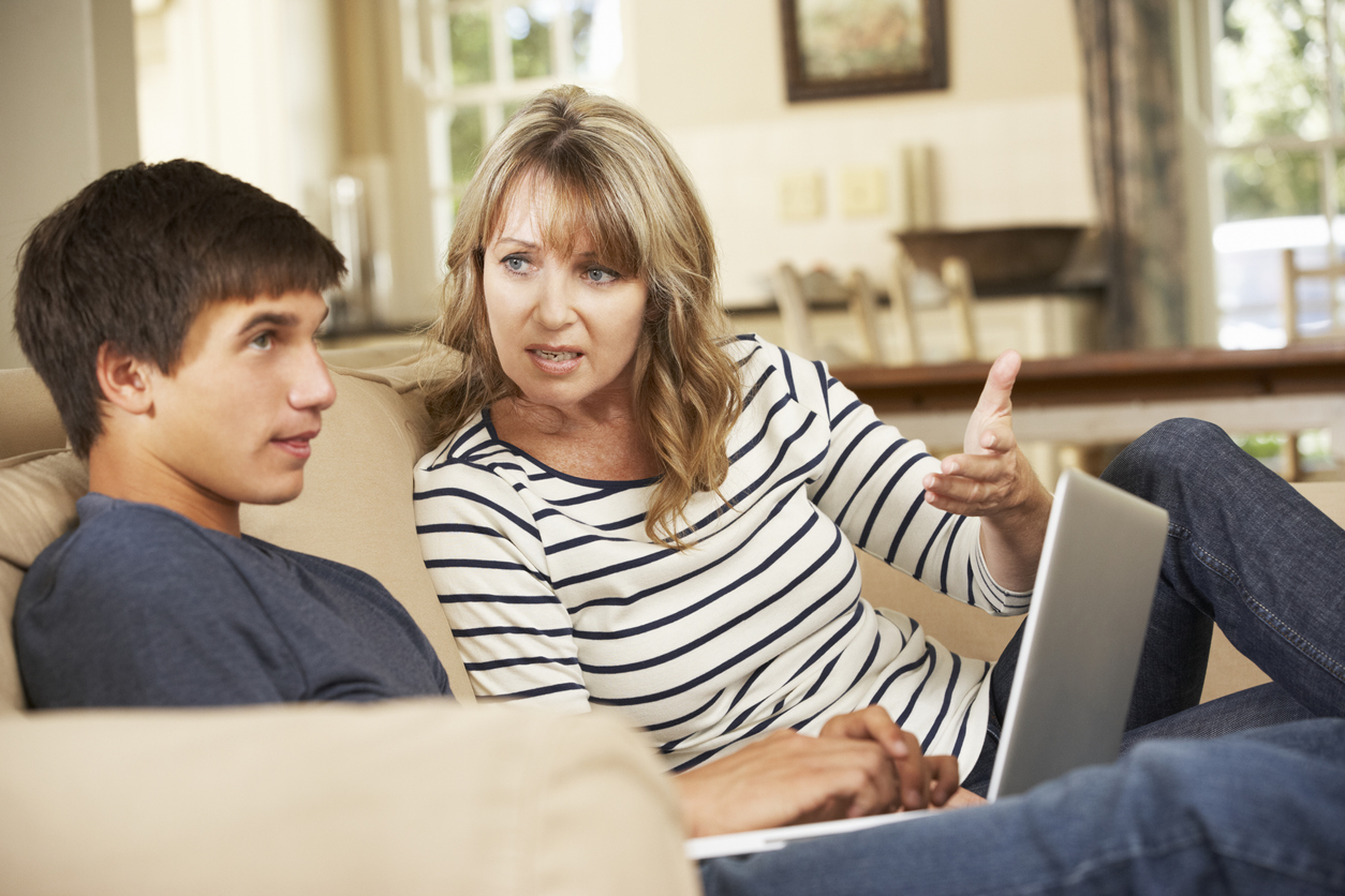 Mother And Teenage Son Arguing On Sofa