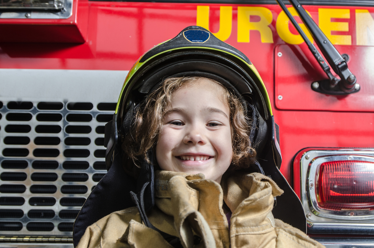 Young girl wearing fireman coat and helmet