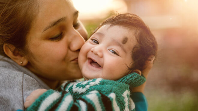 Mom Kisses Smiling Baby Son