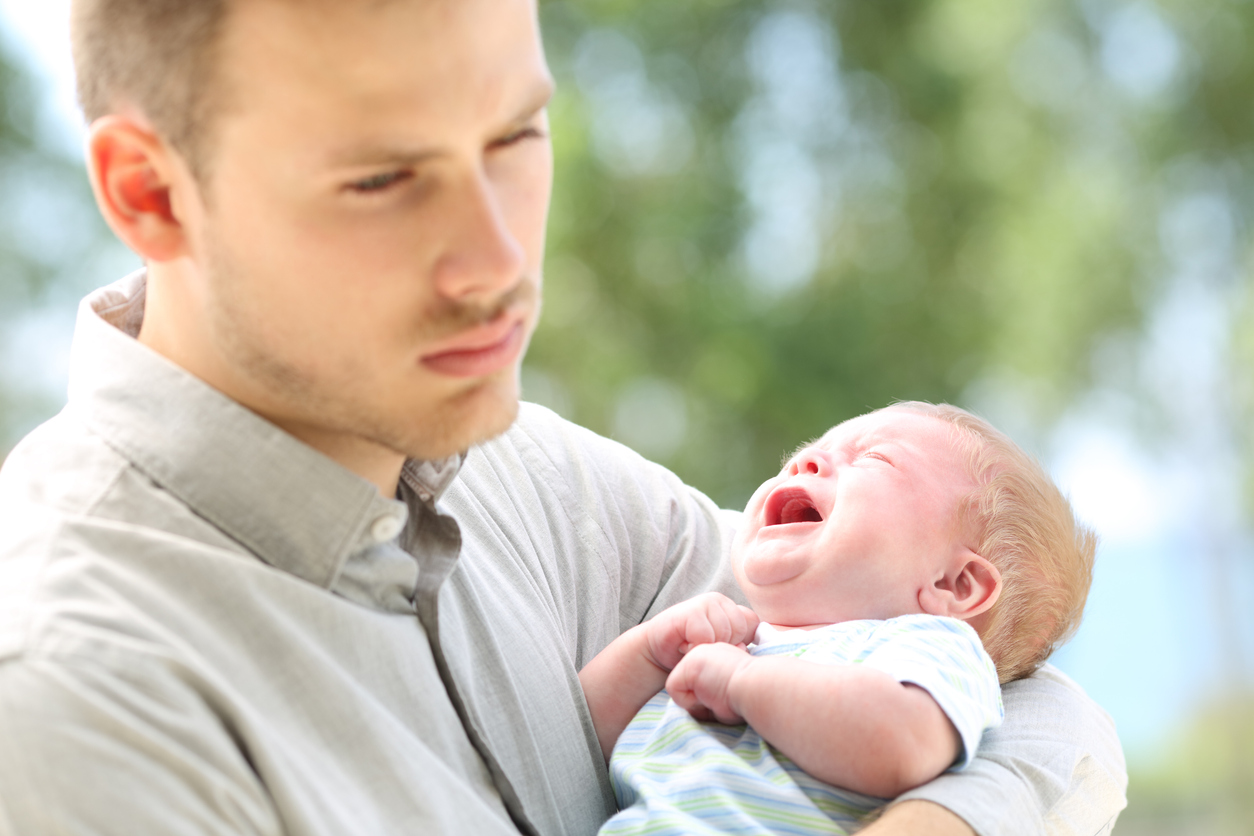 Baby crying and bored father