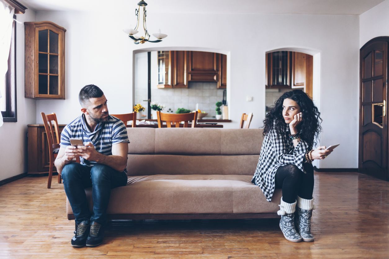 Couple with relationship difficulties sitting on sofa at home