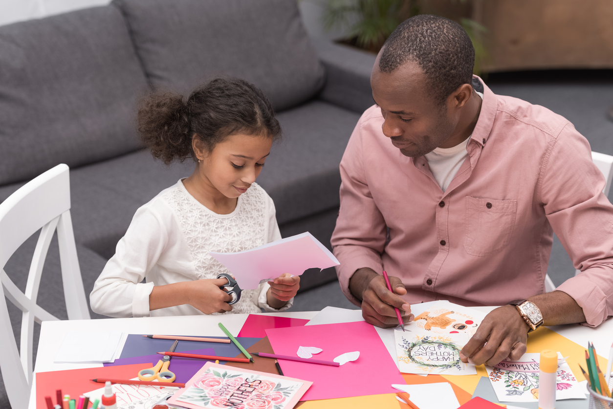 african american daughter cutting paper for greeting card on mothers day