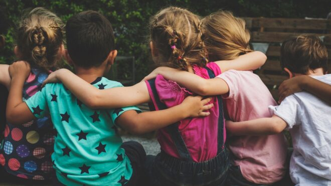 Group of kindergarten kids friends arm around sitting together