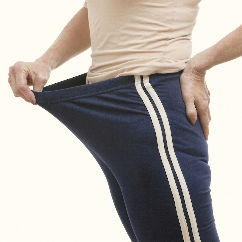 Portrait of senior woman in oversized pants against white background