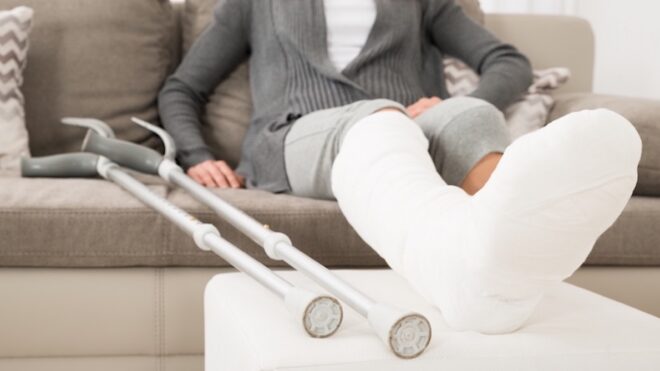 Woman With Plastered Leg Sitting On Couch