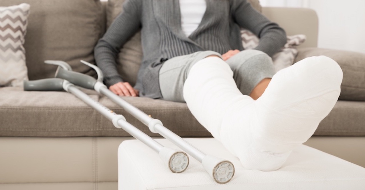 Woman With Plastered Leg Sitting On Couch