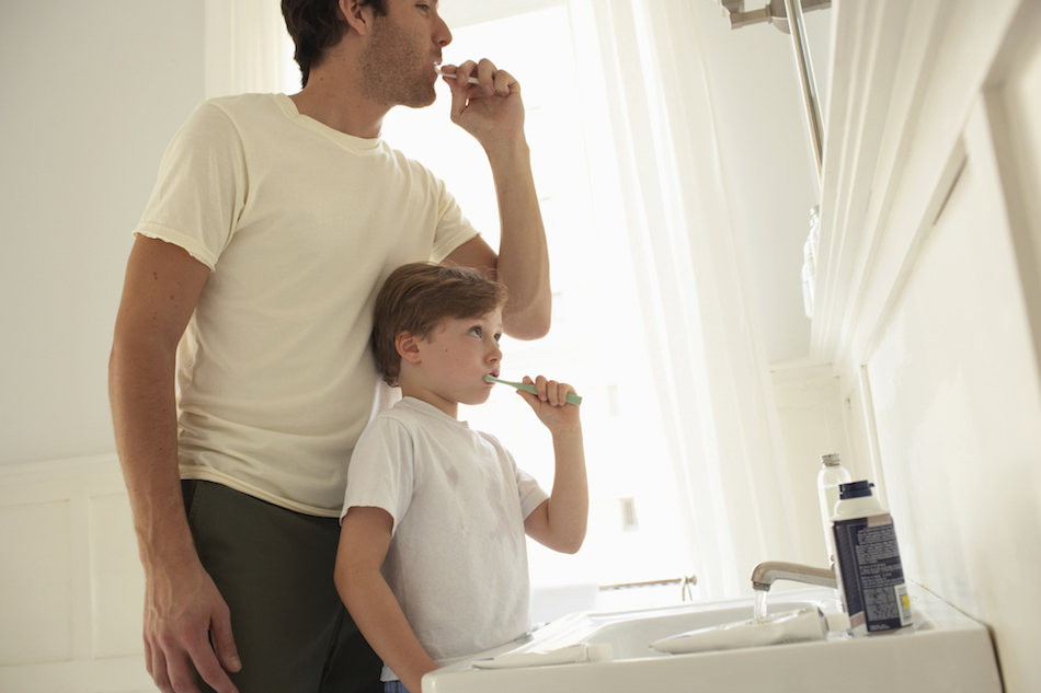 Father and son (5-7) brushing teeth in bathroom, low angle view