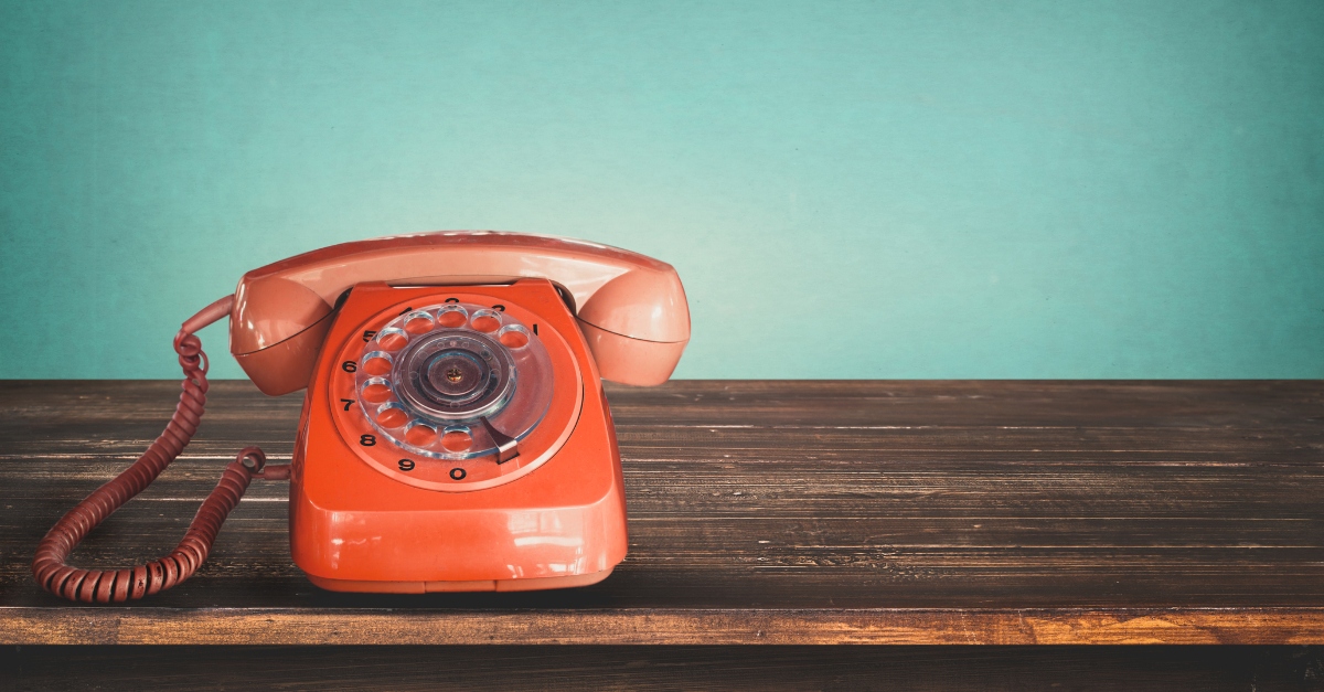 Old retro red telephone on table with vintage green pastel background