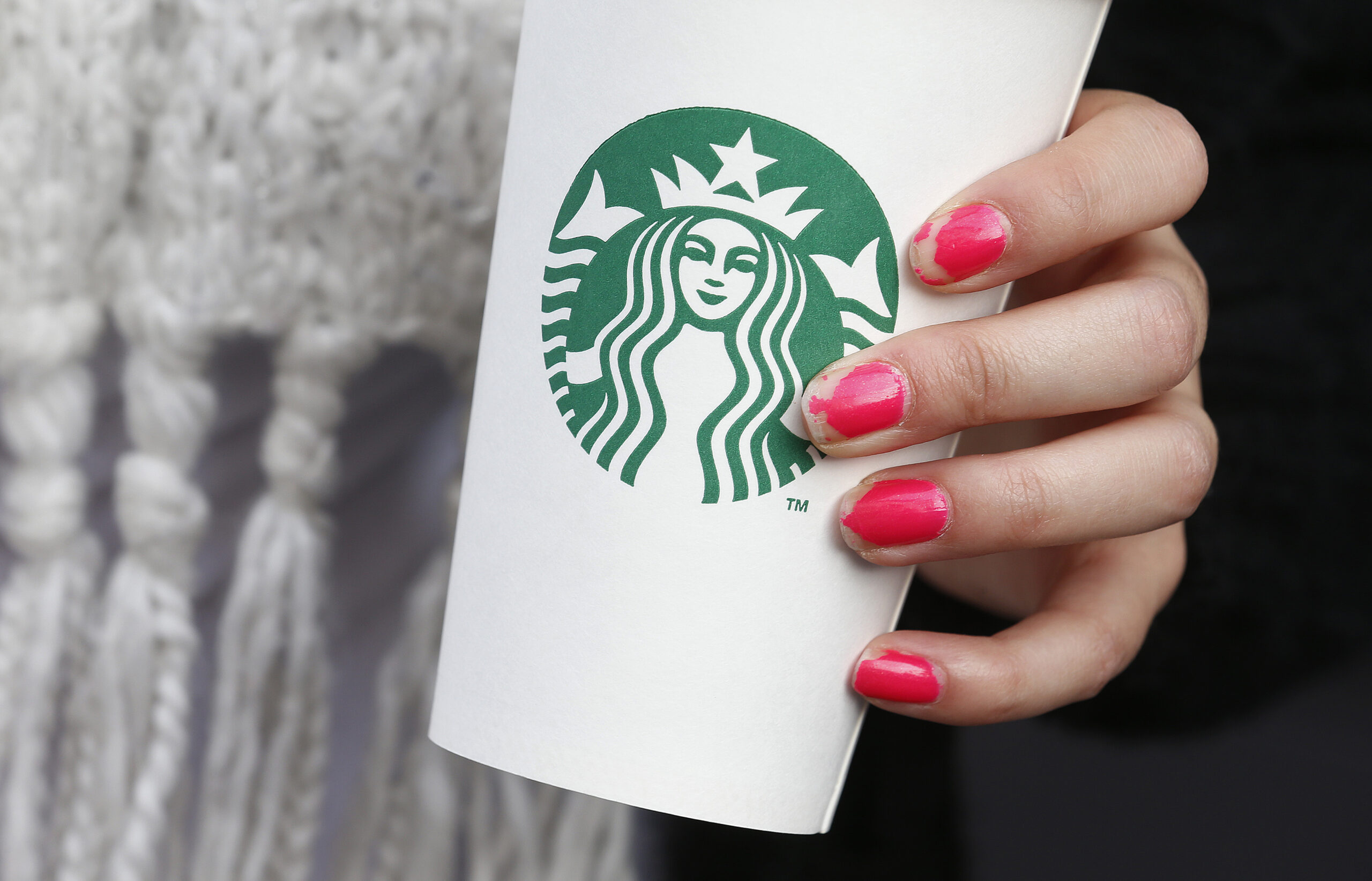 A WOMAN HOLDS A STARBUCKS TAKEAWAY CUP IN LONDON