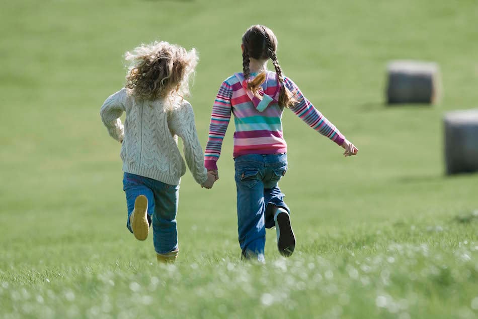 Back view of girls running across field, Ireland