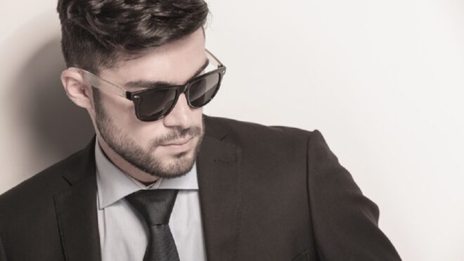 sexy young business man wearing sunglasses looks away