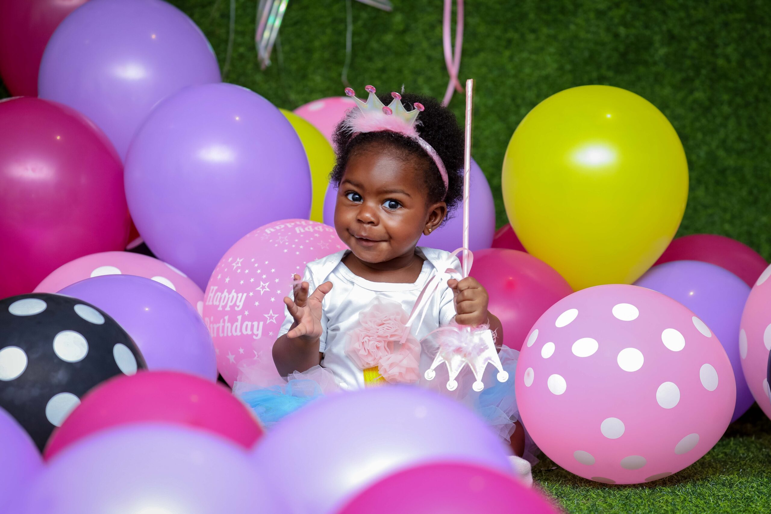 toddler-girl-sitting-on-ground-surrounded-by-balloons-2093717.jpg