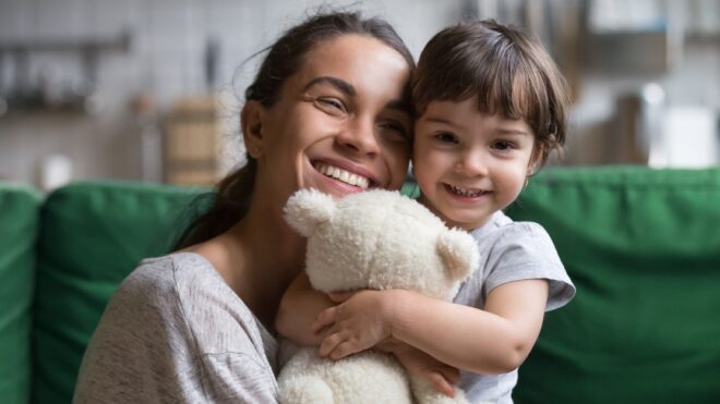 Smiling single young mum embracing little daughter