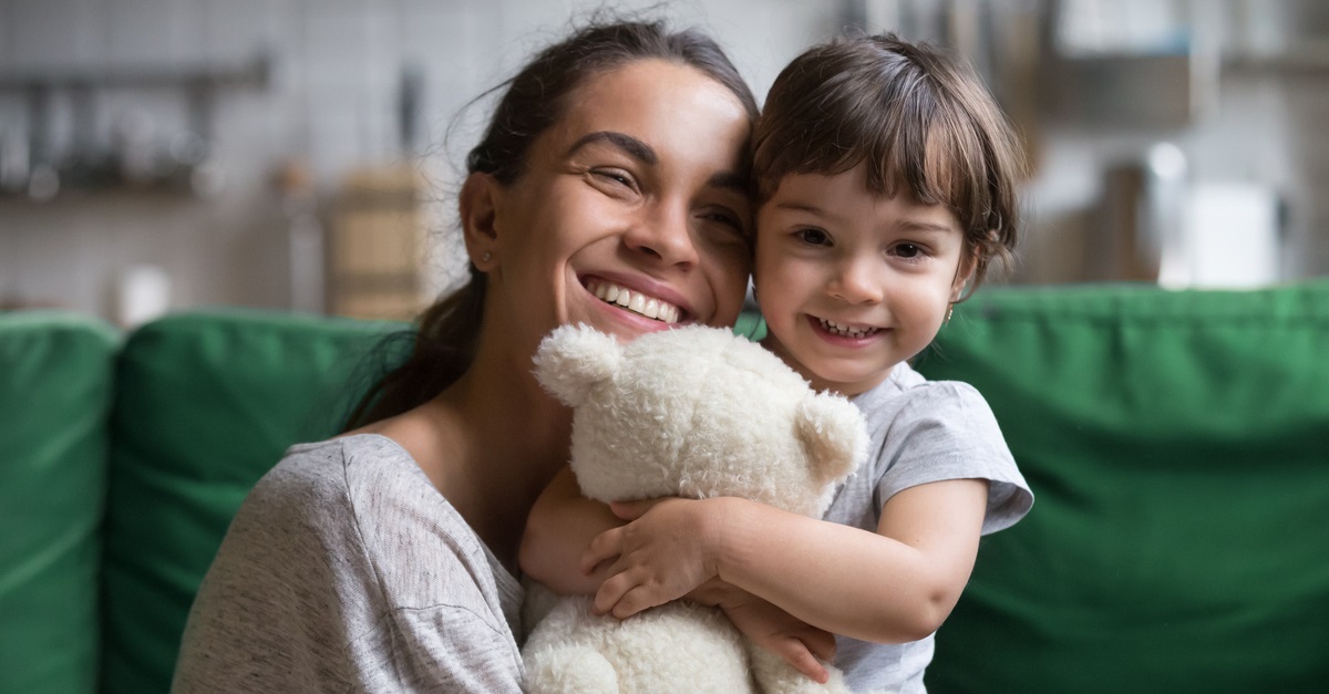 Smiling single young mum embracing little daughter