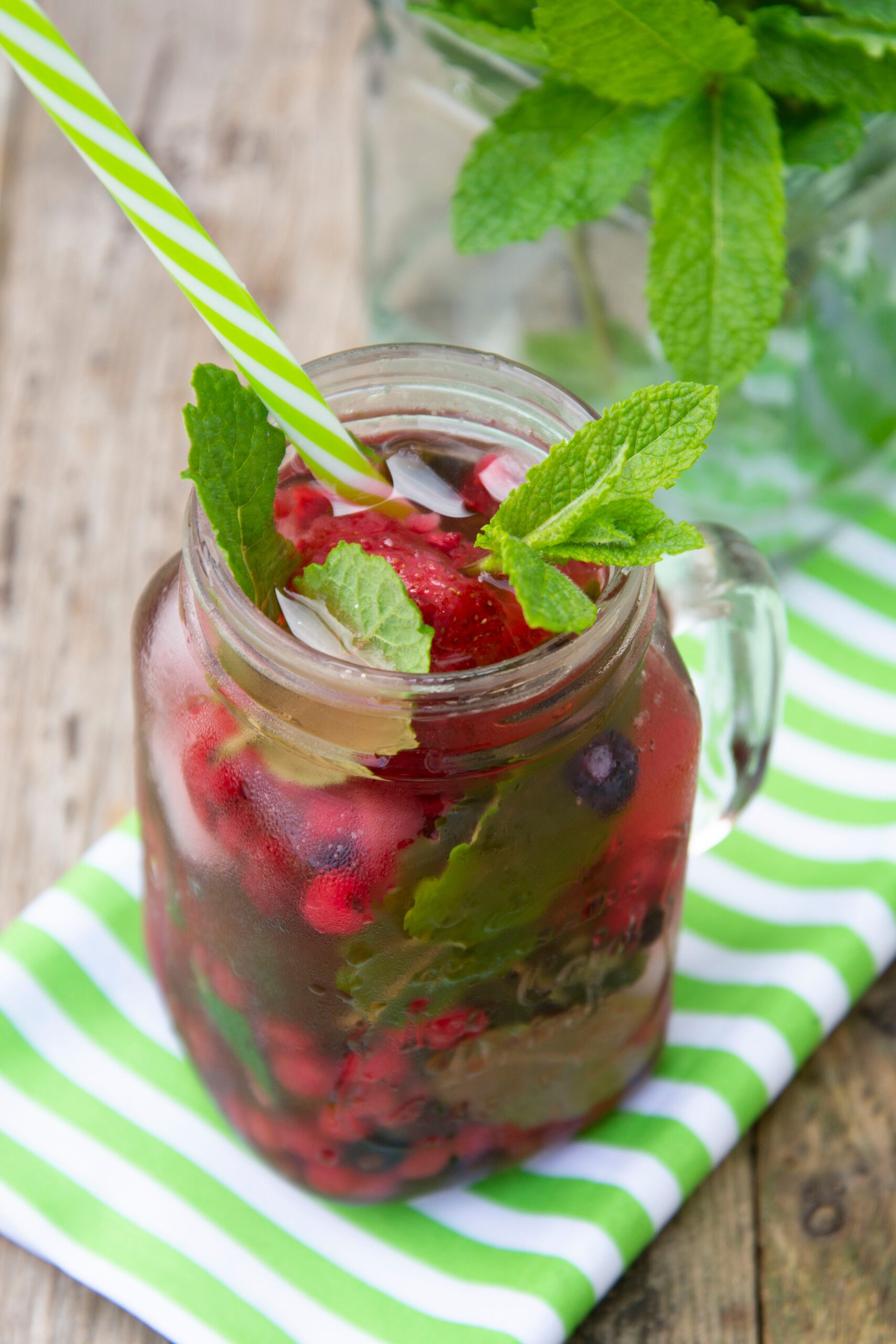 Stylish fresh ice, cold fruit tea background, Mason jar cup with straw, summer fruit tea drink, wooden background