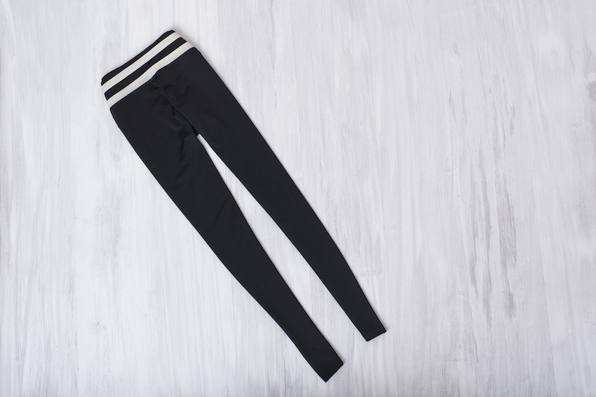 Black gym leggings on wooden background. Fashionable concept