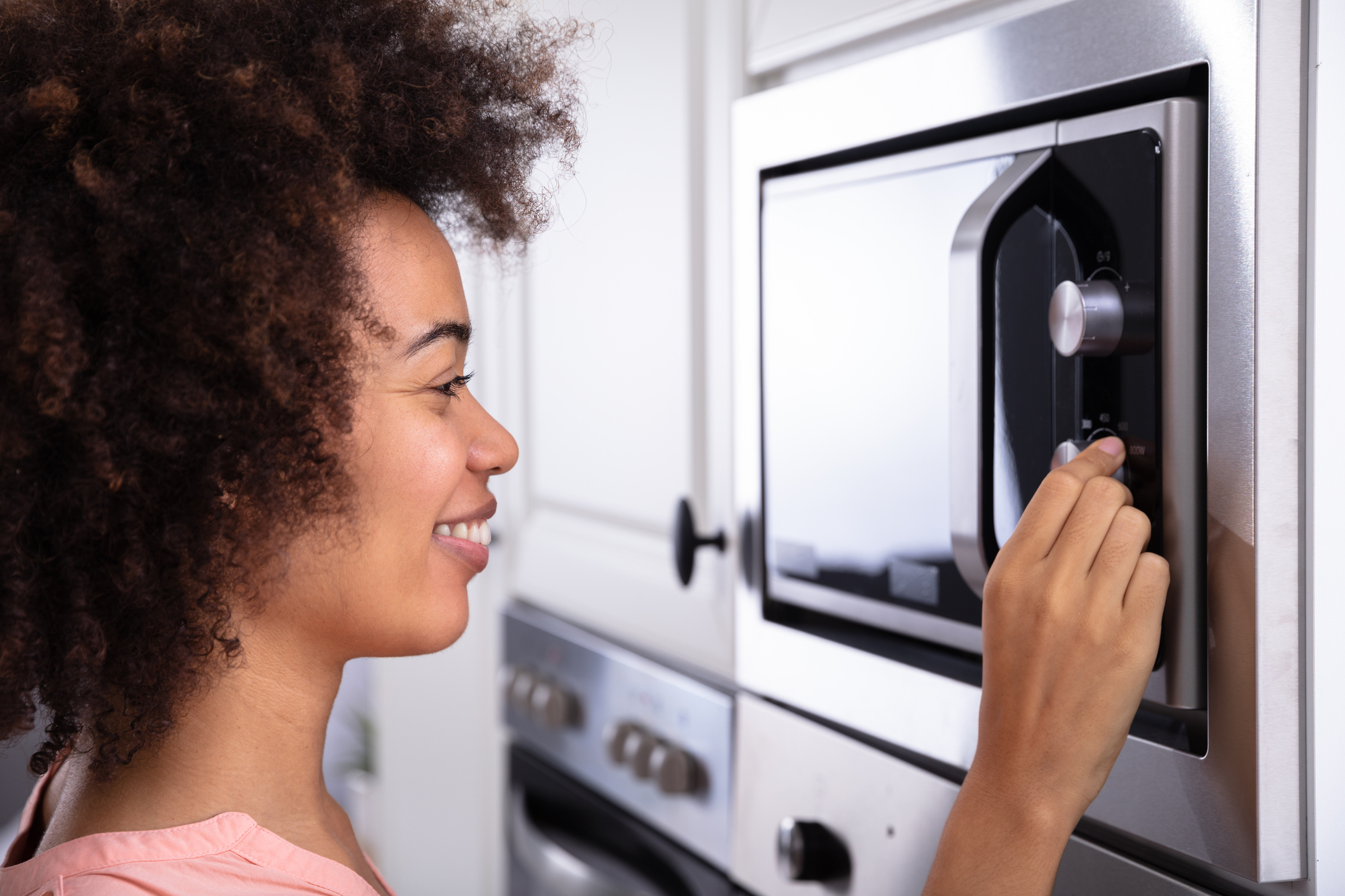 Woman Adjusting Temperature Of Microwave Oven