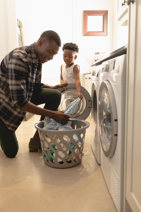 Father and son washing clothes in washing machine