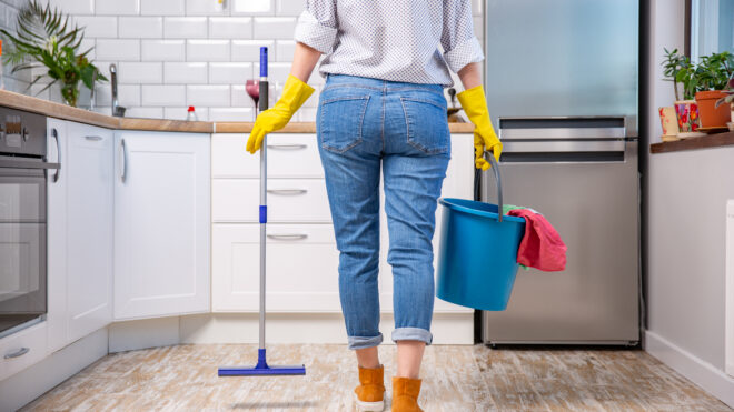 Woman holding mop and bucket with cleaning agents at home
