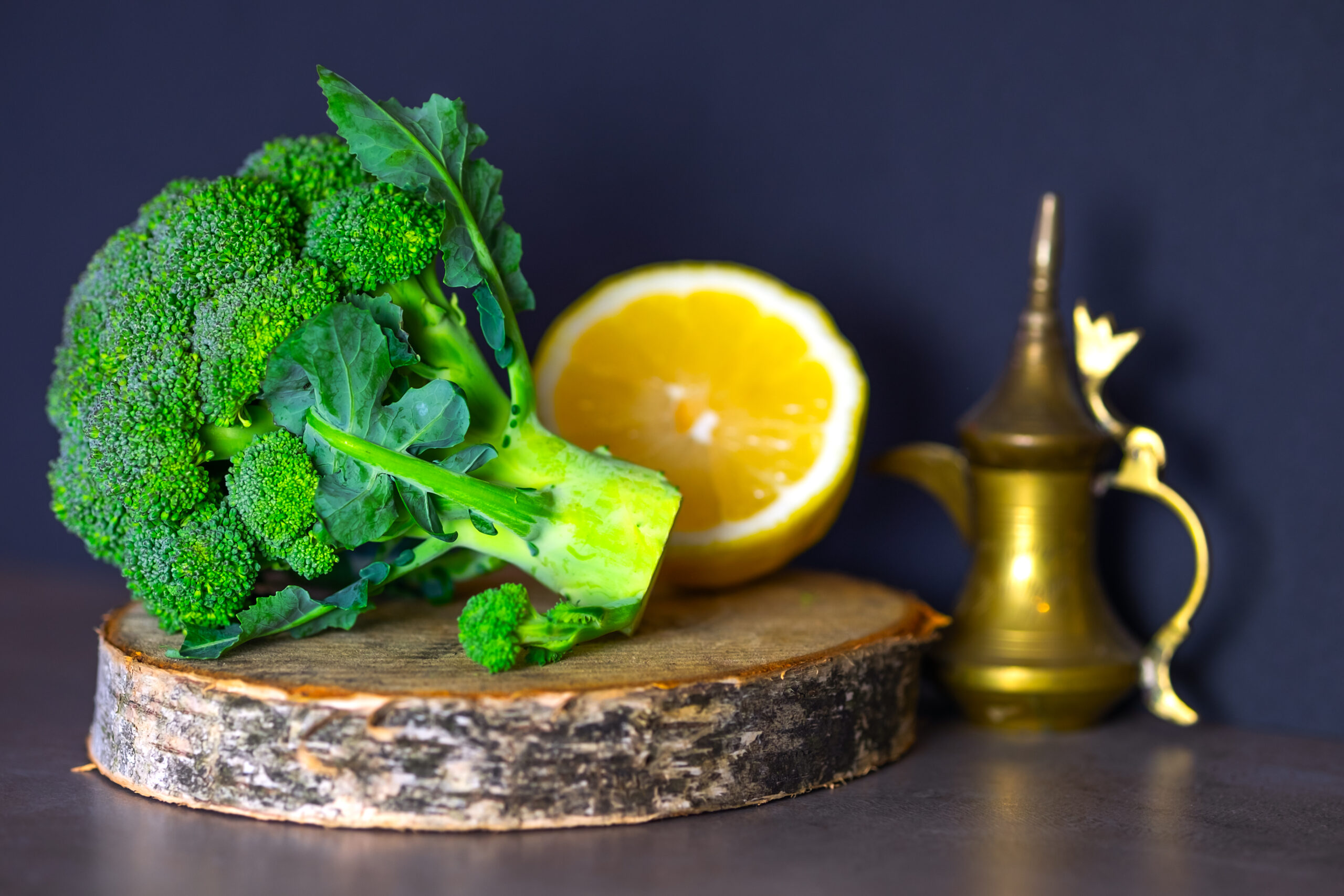 Useful foods are on the table, broccoli on a wooden stand and sliced lemon.