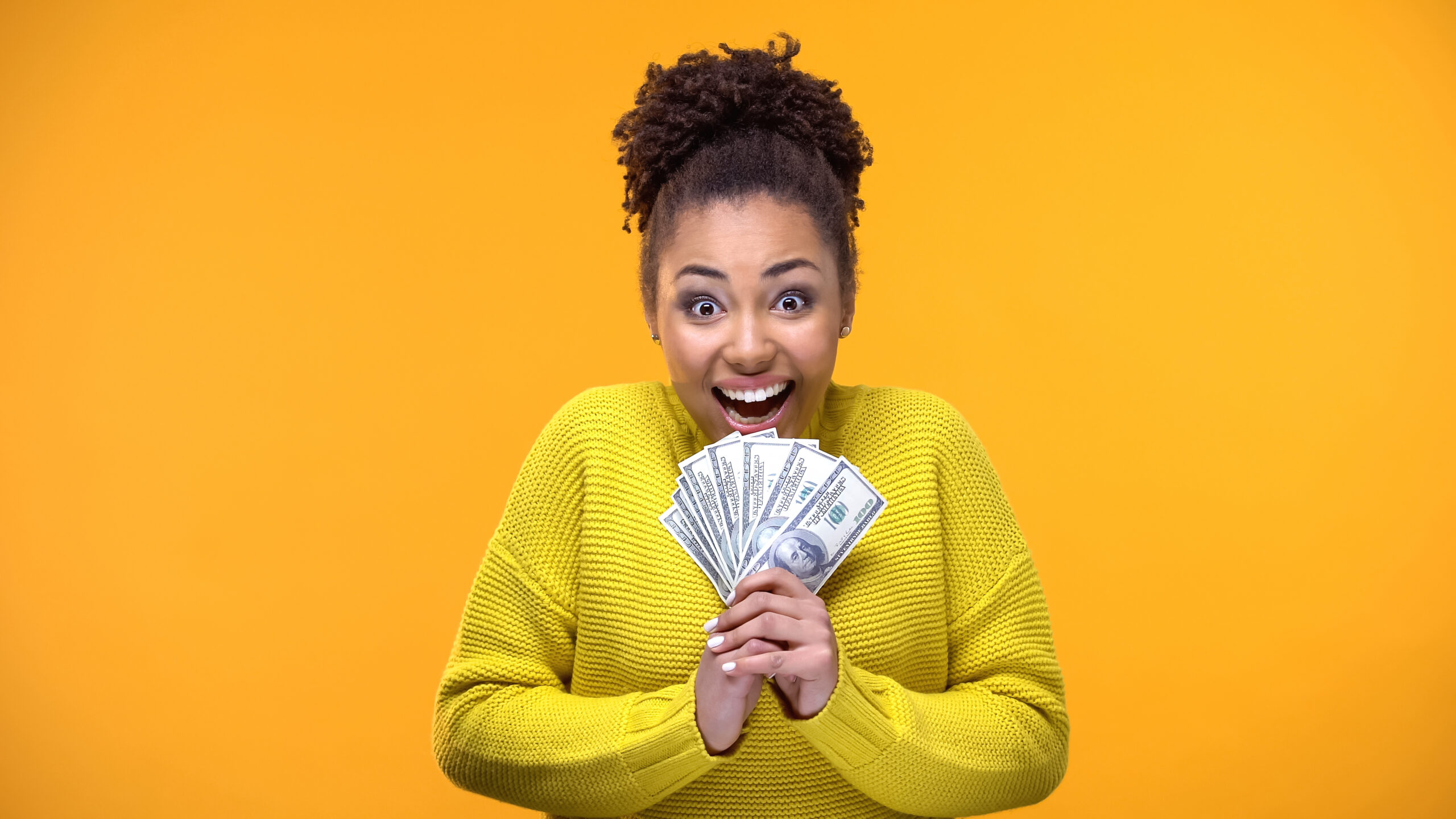 Excited Afro-American woman holding bunch of dollars, lottery winner, fortune