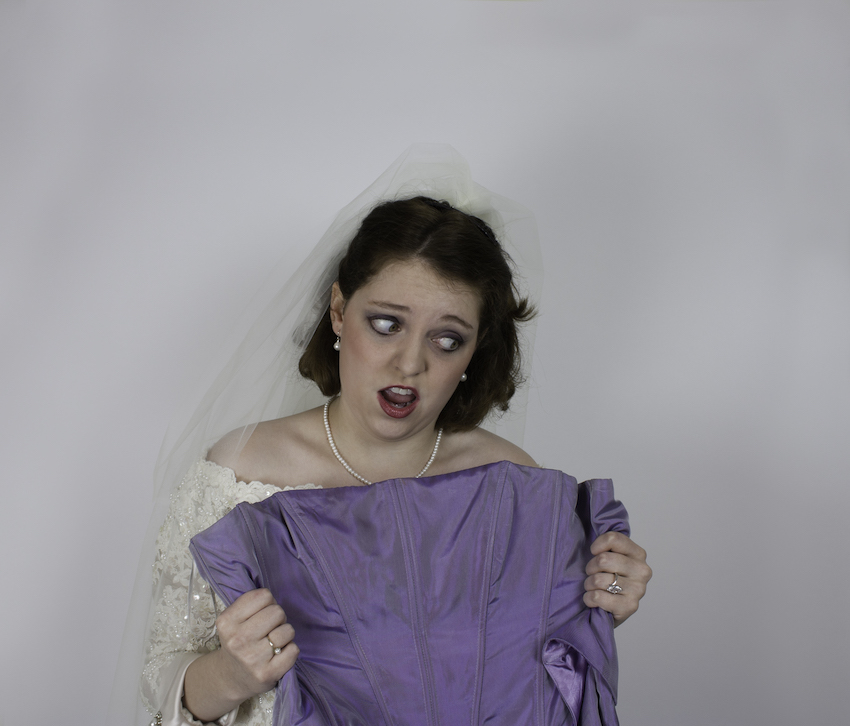 Young bride holds bridesmaid's dress with a mad expression