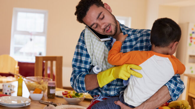 Busy Father Looking After Son Whilst Doing Household Chores