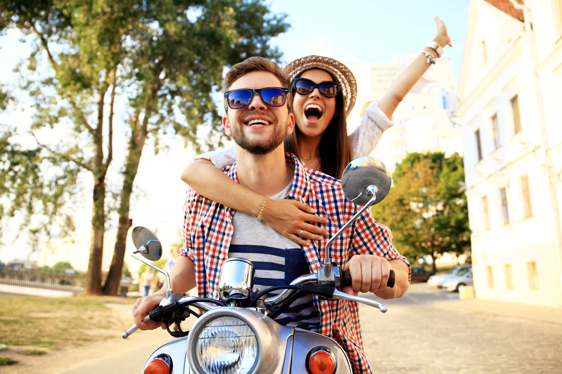 Portrait of happy young couple on scooter enjoying road trip