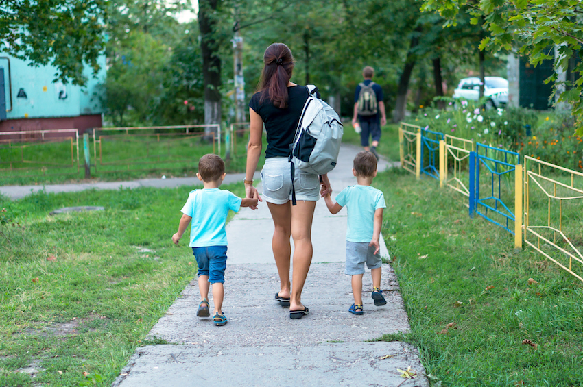 Young mother walking and holding hands two boys