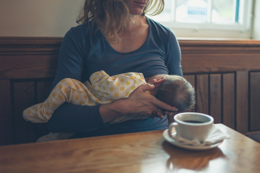 Woman breastfeeding baby in cafe