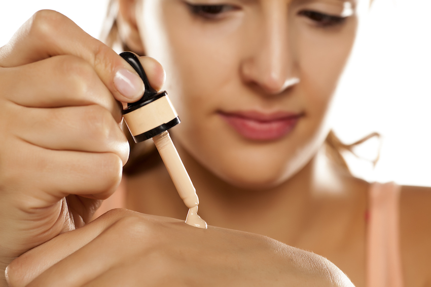 young woman puts a liquid foundation on her palm