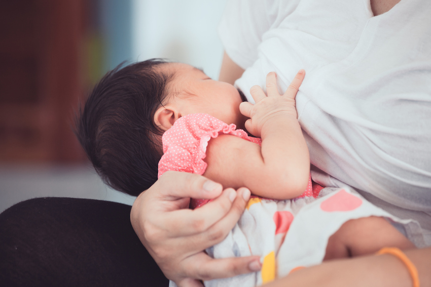 Mother breastfeeding her newborn baby girl.