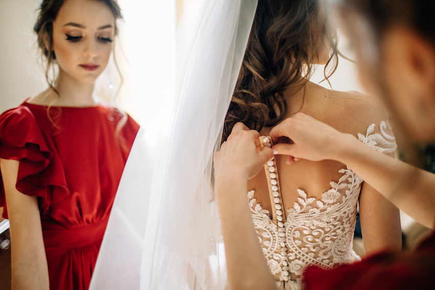 Bridesmaids help bride to get ready for a wedding