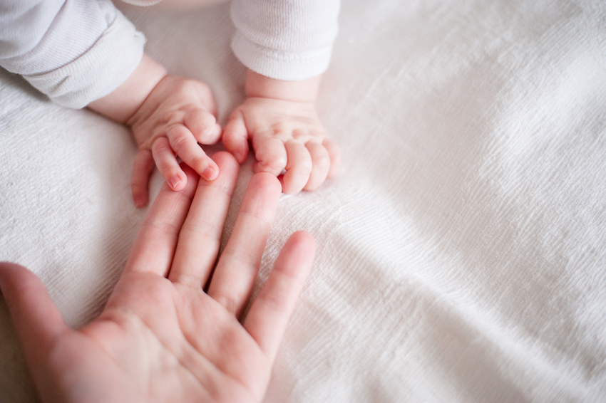 hands of a newborn baby in the mother's fingers