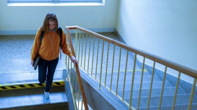 Young depressed lonely female college student walking down the stairs at her school