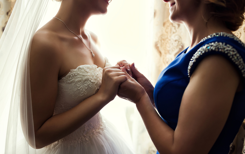 Bride on wedding day holding her mother's hands. Concept of relationship between moms and daughters