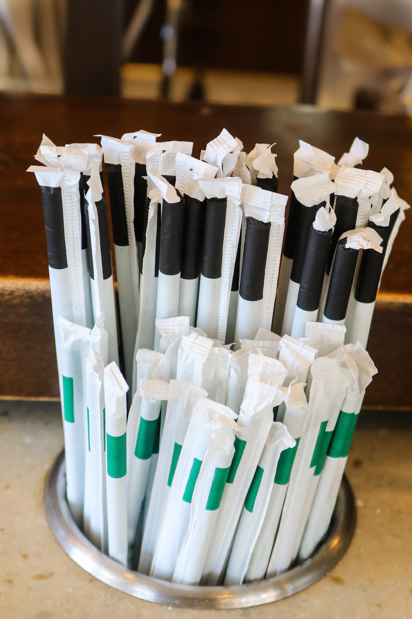 Plastic straws with paper wrappers in counter holder - the straws that many states and countries are outlawing but are still used many places