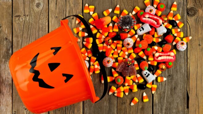 Halloween candy spilling out of a pumpkin pail