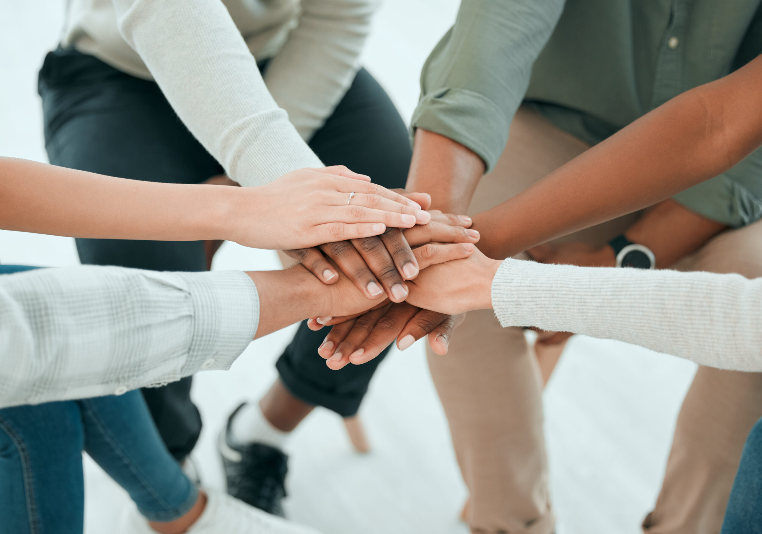 Cropped shot of an unrecognisable group of people sitting together and stacking their hands in the middle