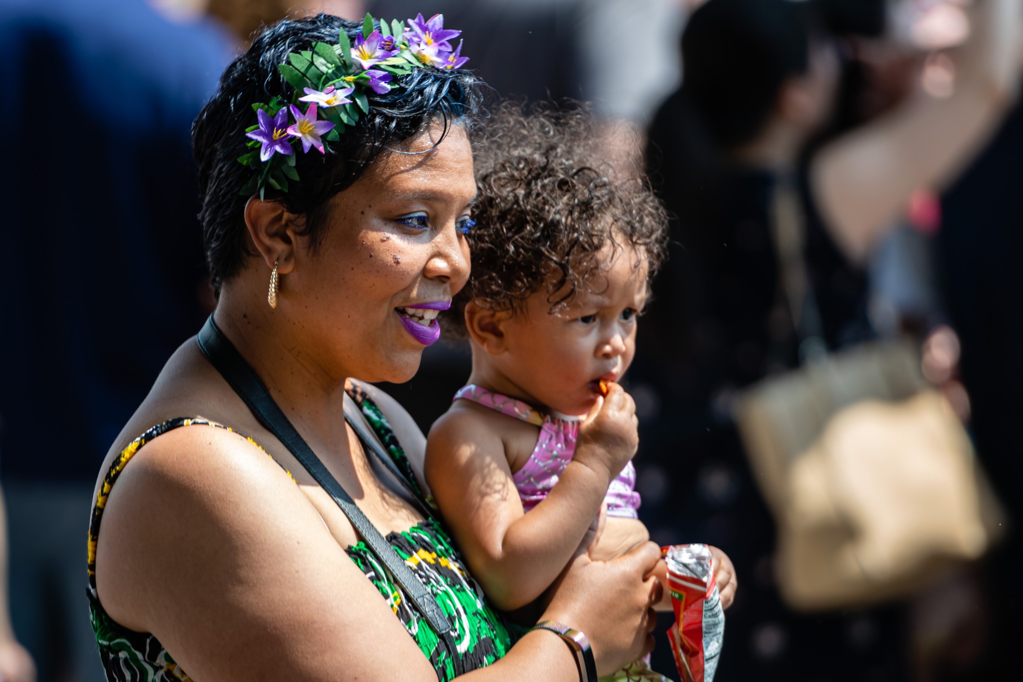 african-woman-with-a-flower-wreath-on-her-head-and-a-baby-on-her-hands-walking-in-the-crowd-on-the_t20_YE3Kj0.jpg