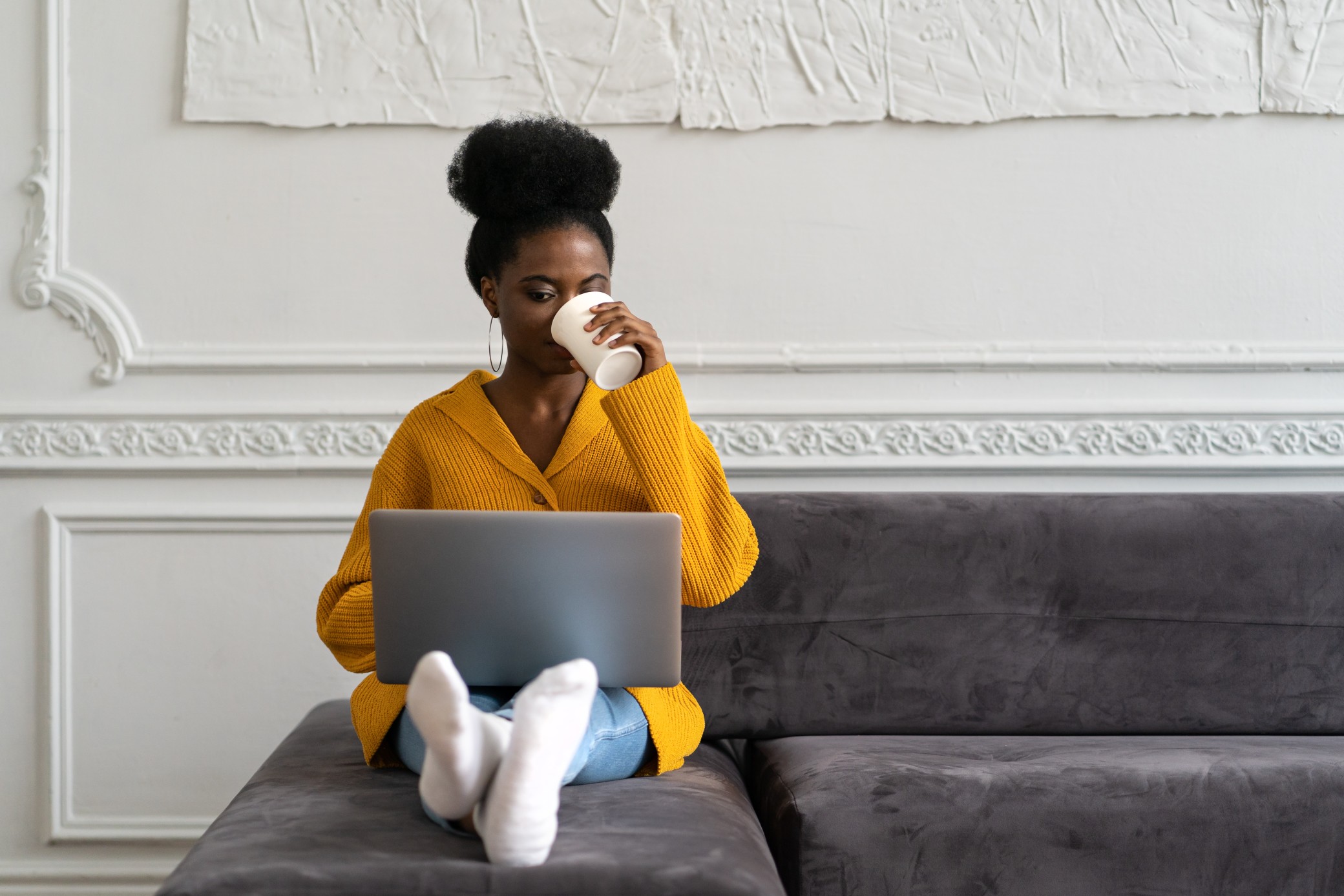 afro-american-biracial-woman-with-afro-hairstyle-in-yellow-cardigan-sitting-on-couch-working-online_t20_vL4lWw.jpg