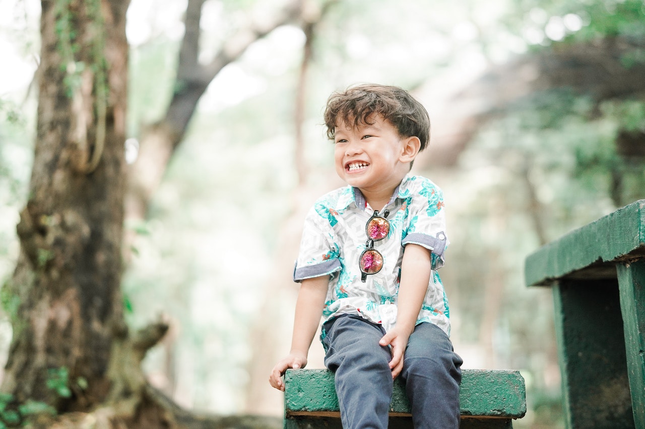 boy-in-floral-button-up-t-shirt-sitting-on-green-concrete-4137752.jpg