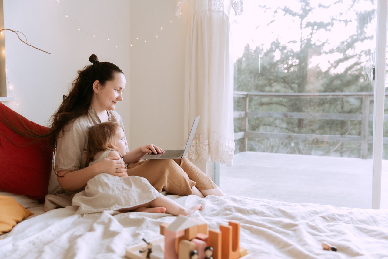 cheerful-mother-cuddling-daughter-while-sitting-on-bed-with-3975675.jpg