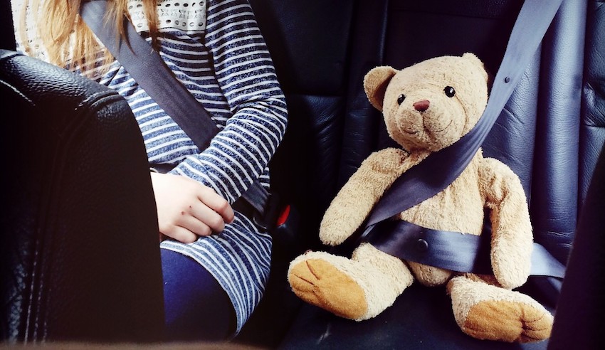 child-sat-next-to-teddy-in-back-of-car-with-their-seat-belts-on_t20_a869WE.jpg